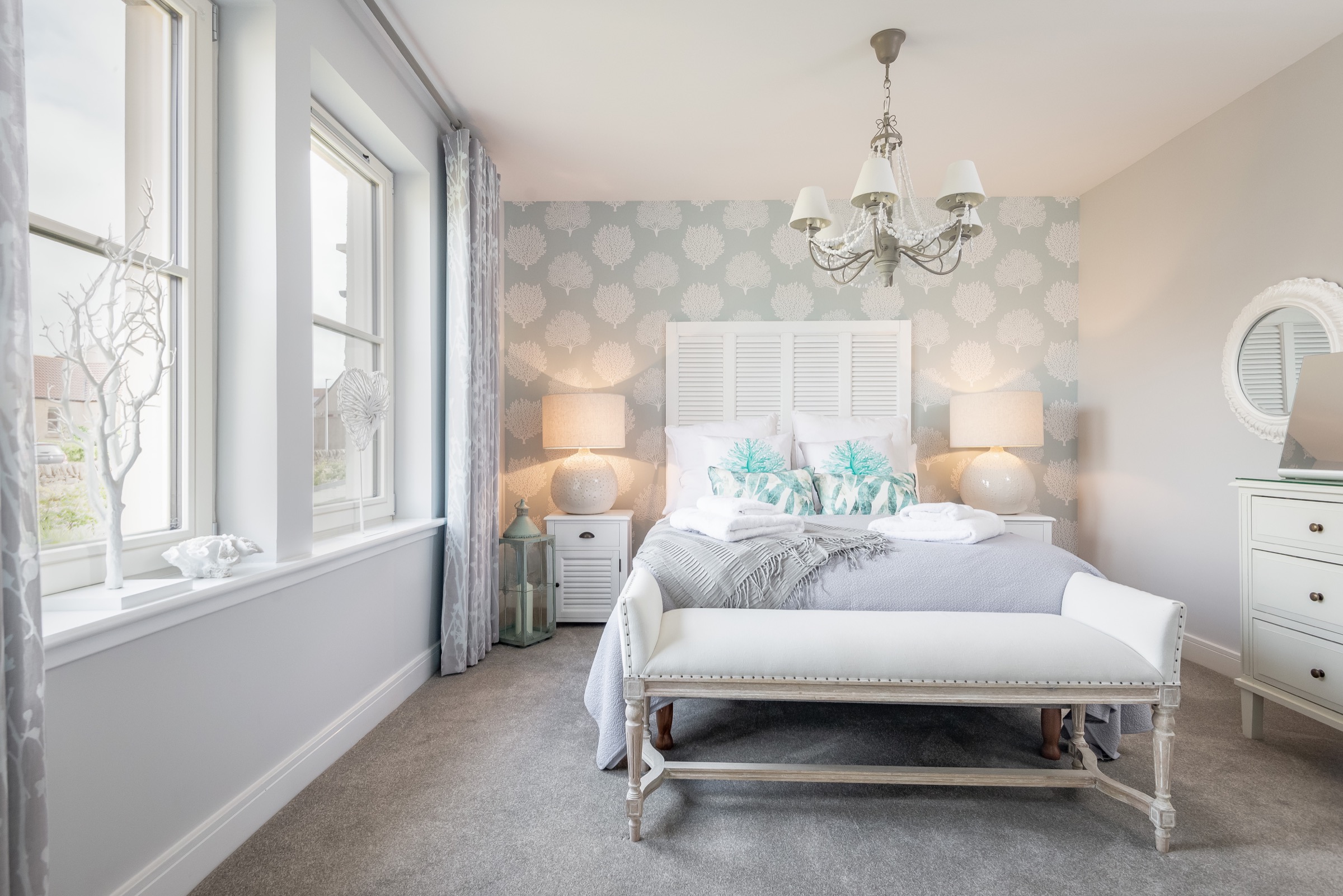 Coastal-themed double bedroom at Dormie House with a chandelier and turquoise accents