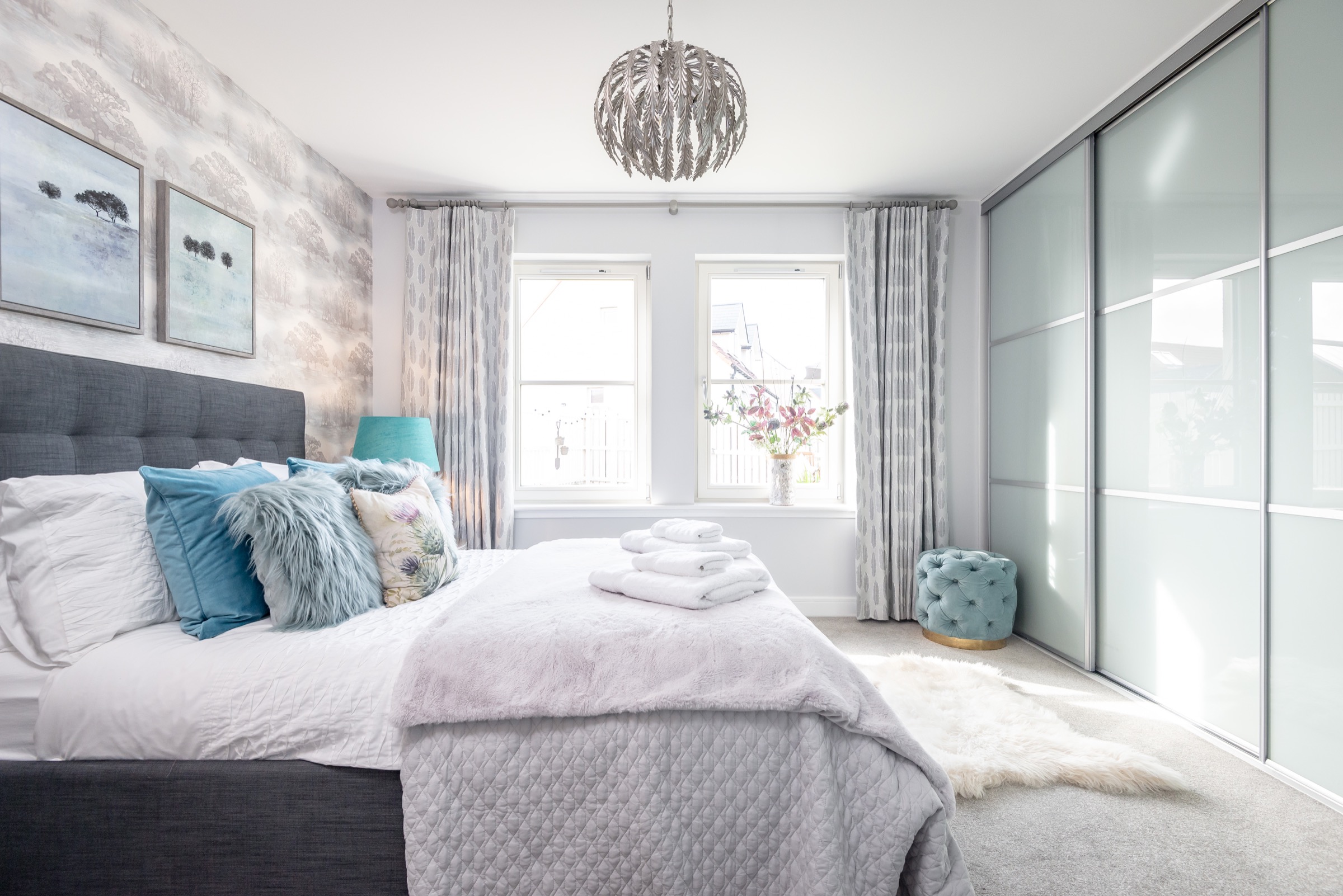 Double bedroom at Dormie House with a grey upholstered bed and thistle-print cushions